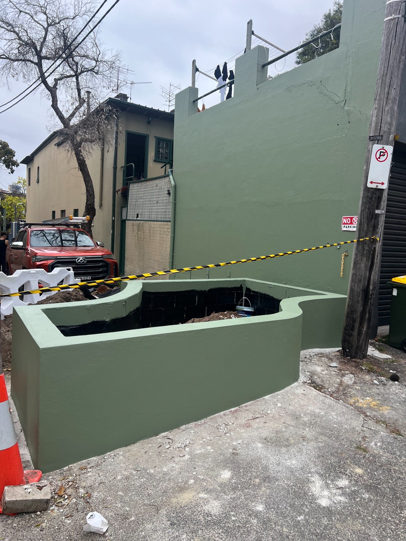 The curved planter with its green painted exterior, before soil and planting are completed